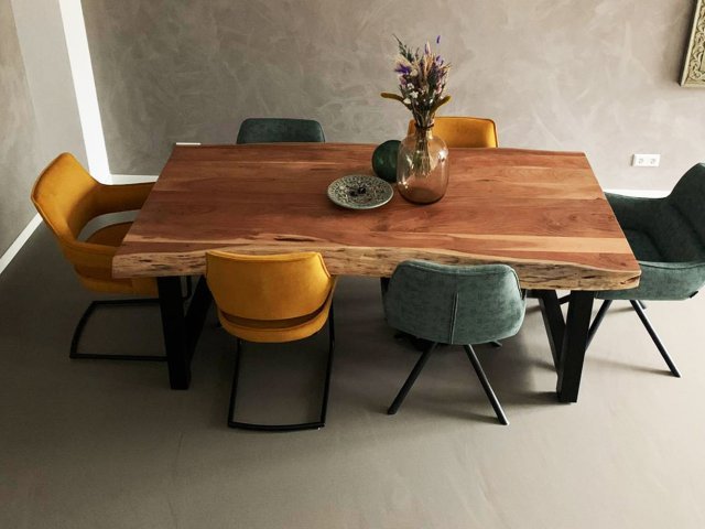 Grijsbruine gietvloer in een eetkamer met houten boomstamtafel en okergele stoelen
