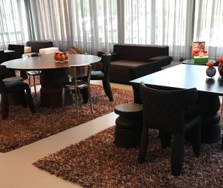 Zandkleurige gietvloer in een loungeruimte met zittafels en hoogpolige kleden
