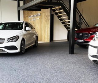 Grijze grindvloer in de showroom van Autocenter Oss met Mercedes en Volkswagen