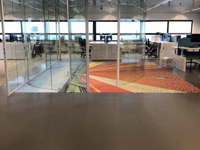 Taupe epoxyvloer in een kantoortuin met glazen scheidingswanden en werkplekken