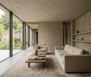 Woonkamer met beige microcement vloer en wanden en doorlopende tuindeuren