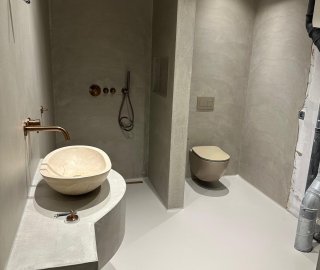 Badkamer met microcement wanden, inloopdouche en witte gietvloer