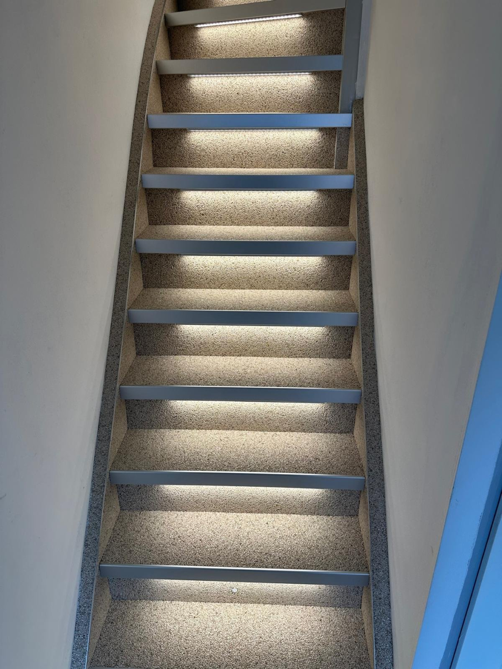 Trap met grindafwerking en led-verlichting onder elke trede, van onderaf gezien